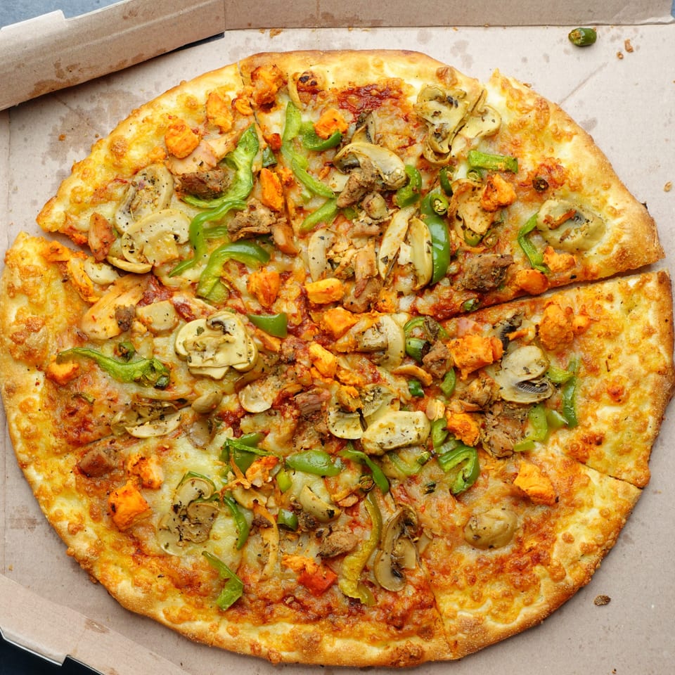 Vincents' pizza with chicken, mushrooms, green peppers, and onions in a cardboard box.
