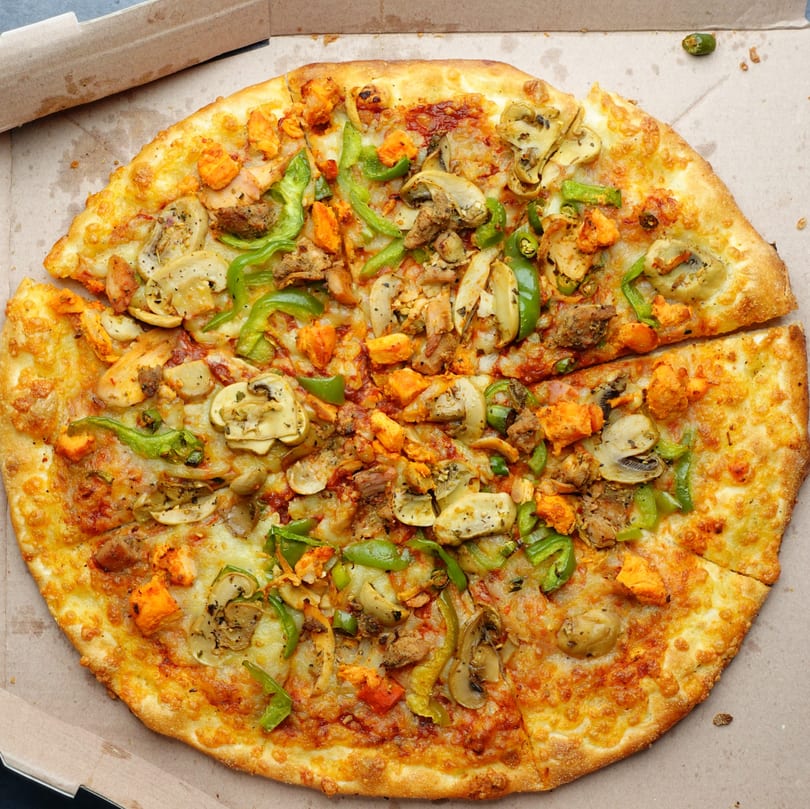 Vincents' pizza with chicken, mushrooms, green peppers, and onions in a cardboard box.